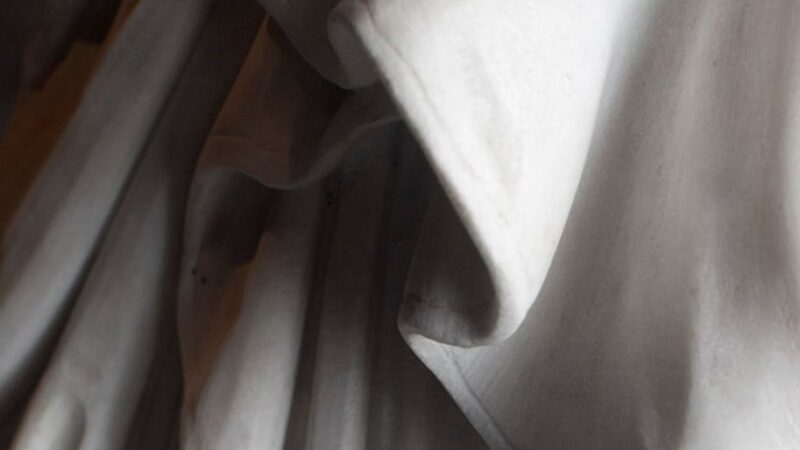 Rome, Italy: monumental cemetery "Verano". Detail of an old statue sculptured between the 18th and the 19th century. Close up on the drapery of the suit. Unknown author.