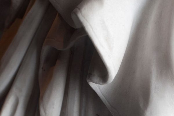 Rome, Italy: monumental cemetery "Verano". Detail of an old statue sculptured between the 18th and the 19th century. Close up on the drapery of the suit. Unknown author.